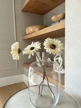 Load image into Gallery viewer, Tall curved glass vase styled on a coffee table with 3 Gerber flower stems placed in it
