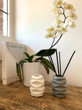 Load image into Gallery viewer, A gloss reed diffuser vessel in grey or white with a wave design around the edge. 
