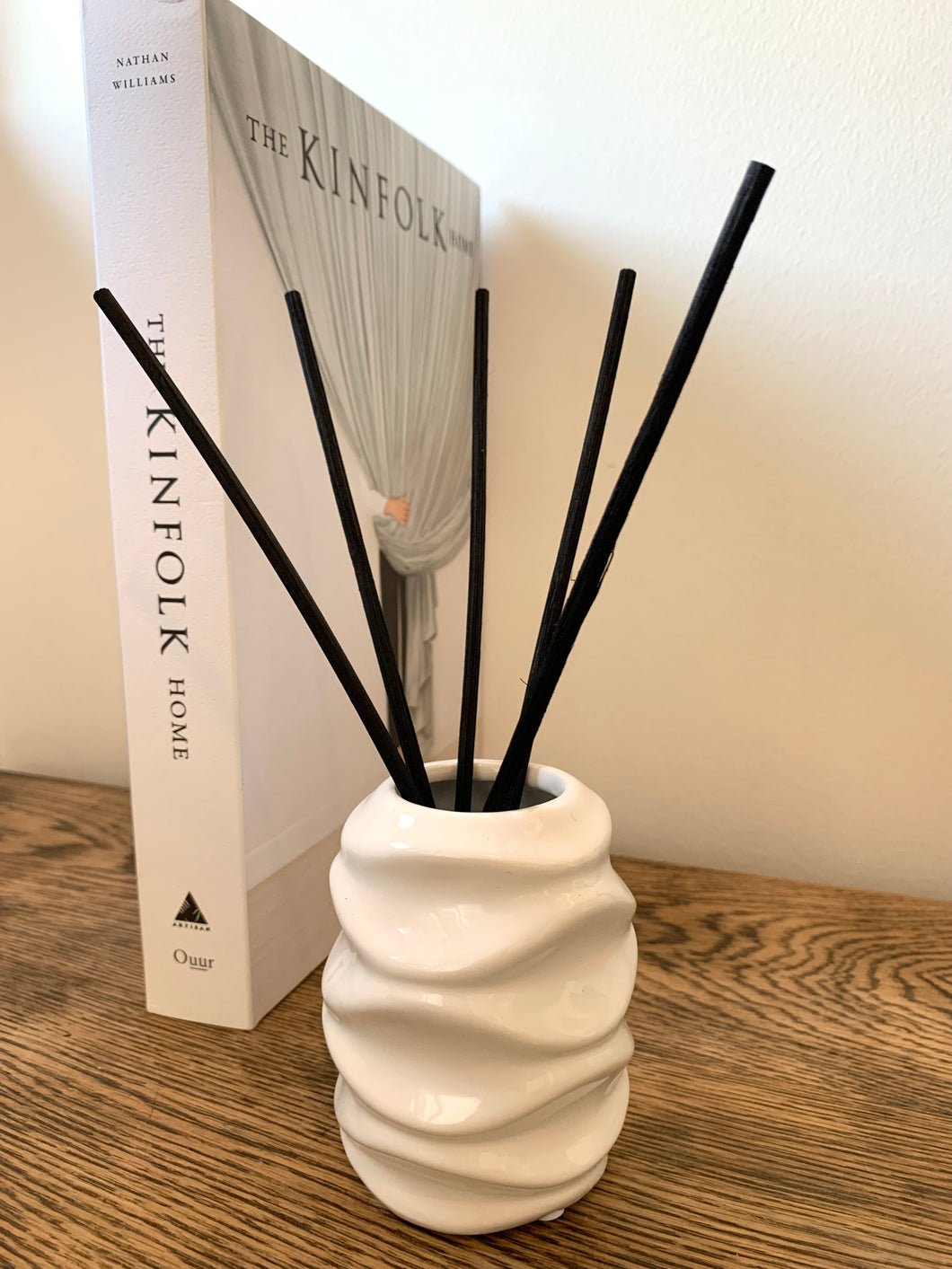A gloss reed diffuser vessel in grey or white with a wave design around the edge. 