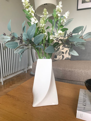 A gloss white contemporary vase with a twist design, Wider at the bottom, Sorrel rises to a narrower opening, creating an elegant flow to the rhythm of the vase