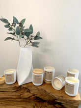 Load image into Gallery viewer, whole collection of candle jars, white with wooden lids,  6 of them styled on top of a large piece of sculptured wood.
