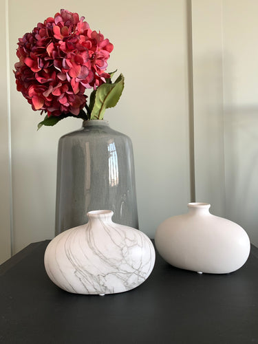 2 curved matt vases, narrow at the top and bigger at the button. One vase is Matt White and one is marble effect.