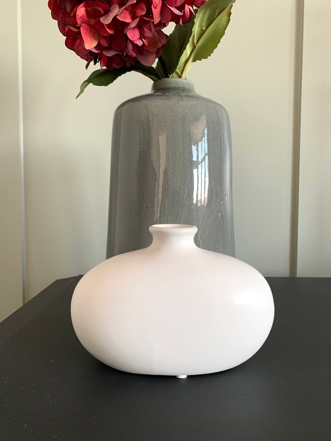 2 curved matt vases, narrow at the top and bigger at the button. One vase is Matt White and one is marble effect.